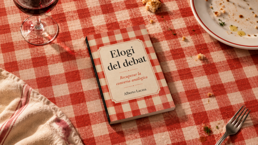 Elogi del debat, d’Alberto Lacasa, sobre una taula amb estovalles de quadres vermells